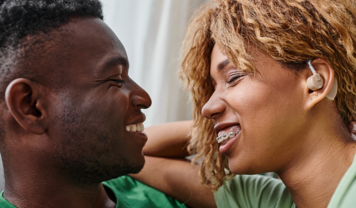 Paar laechelt sich an, Frau traegt ein Hoergeraet