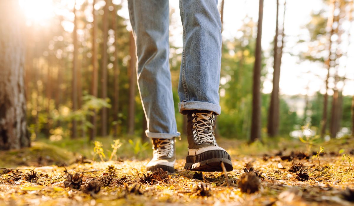 Wanderer mit robusten Schuhen geht durch einen sonnigen Wald