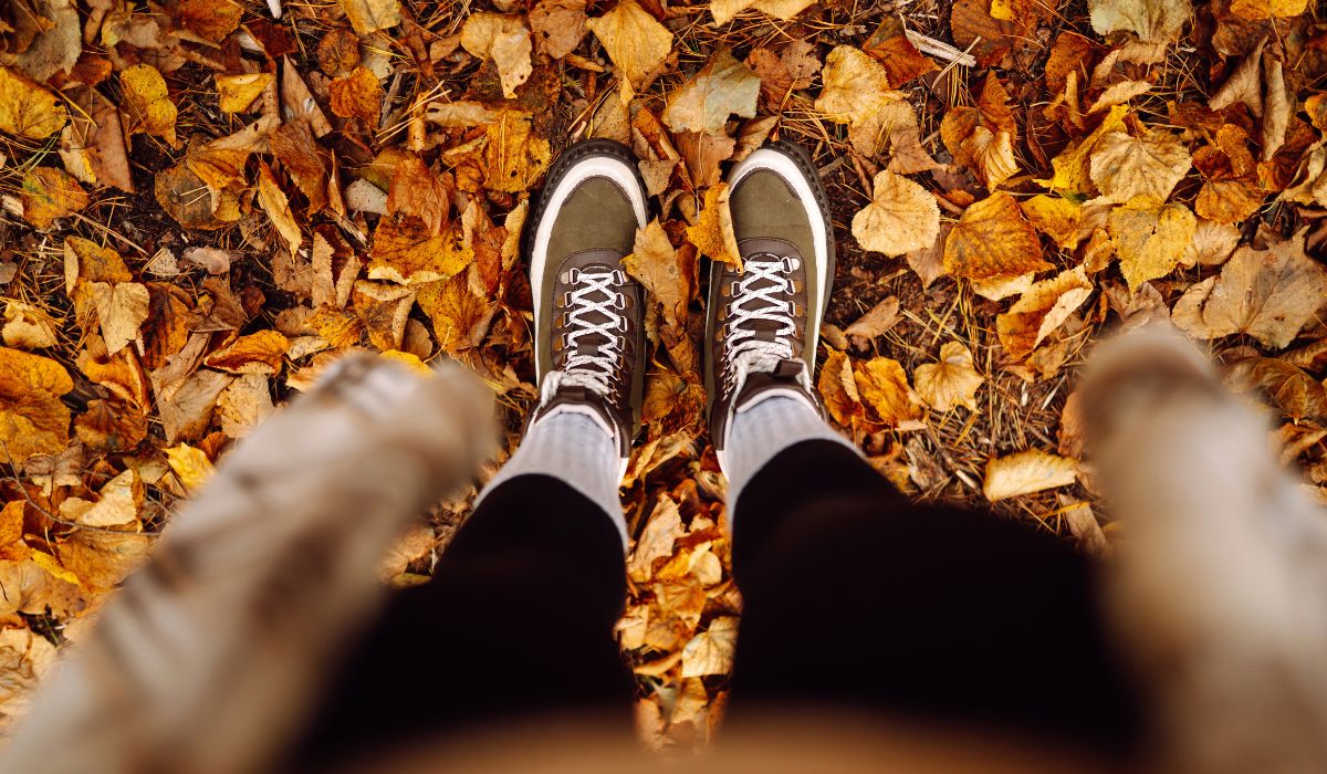 Wanderschuhe auf herbstlich bedecktem Waldboden mit bunten Blaettern