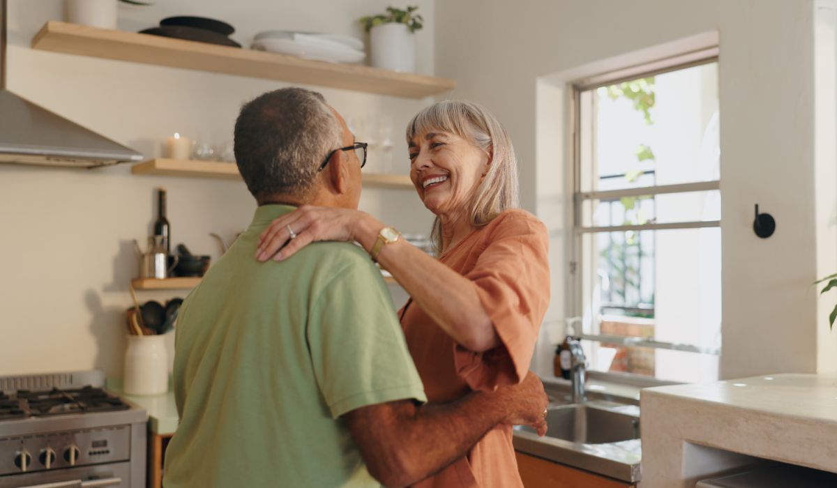 Älteres Paar tanzt lächelnd zusammen in der Küche