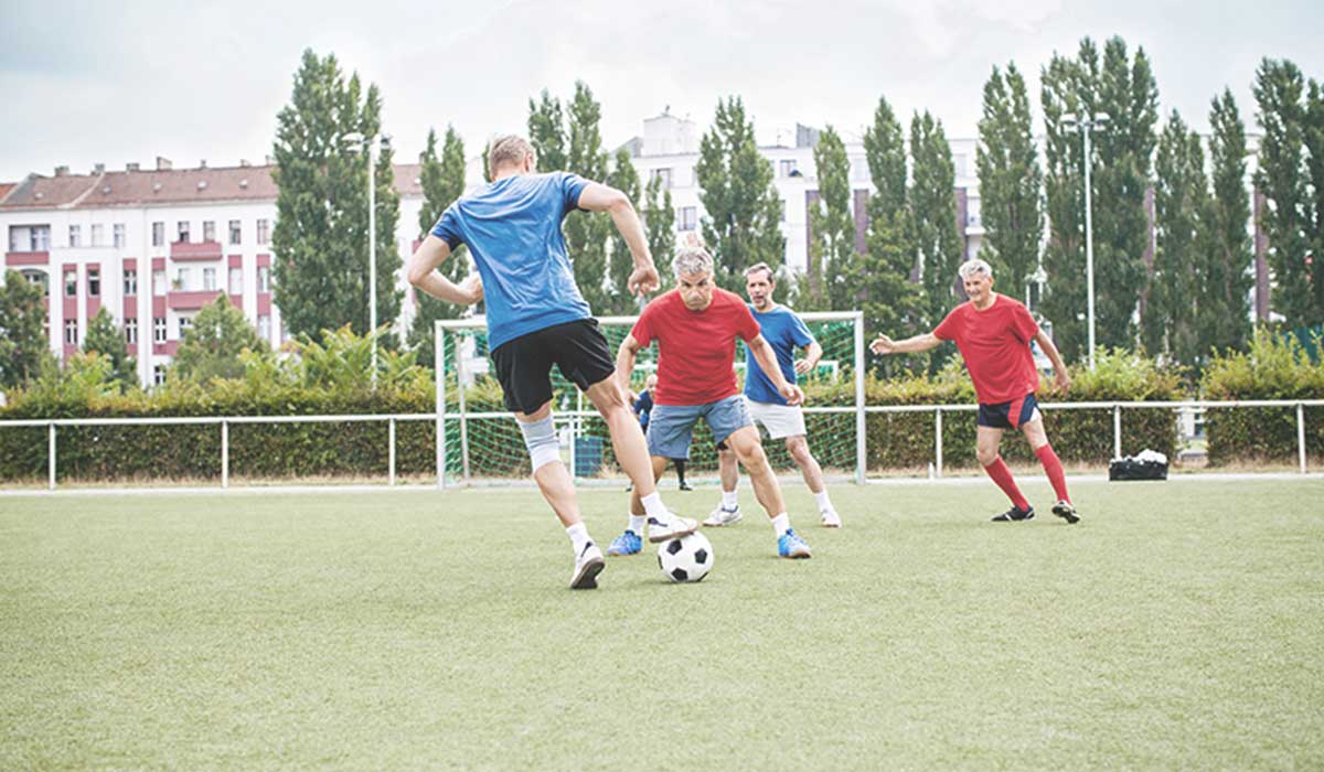 Gruppe älterer Männer spielt Fußball auf einem Sportplatz