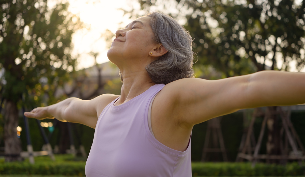 Ältere Frau streckt die Arme aus und geniesst die frische Luft